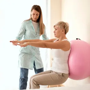 Fisioterapeuta orientando paciente em exercício com bola