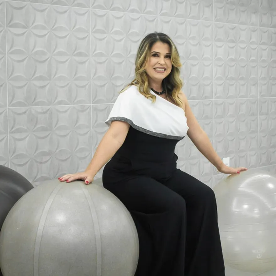 Flávia Renata sentada sobre uma bola suíça no estúdio