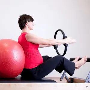 Aluna realizando exercício com anel de Pilates e bola suíça
